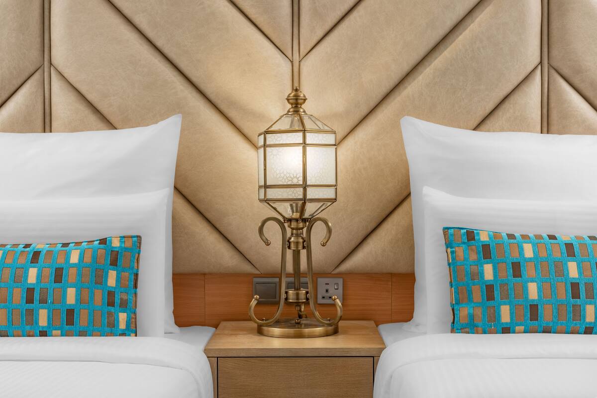 Une chambre d’hôtel équipée d’un lit, d’une table de chevet, d’une lampe fixée au mur et d’une prise de courant.
