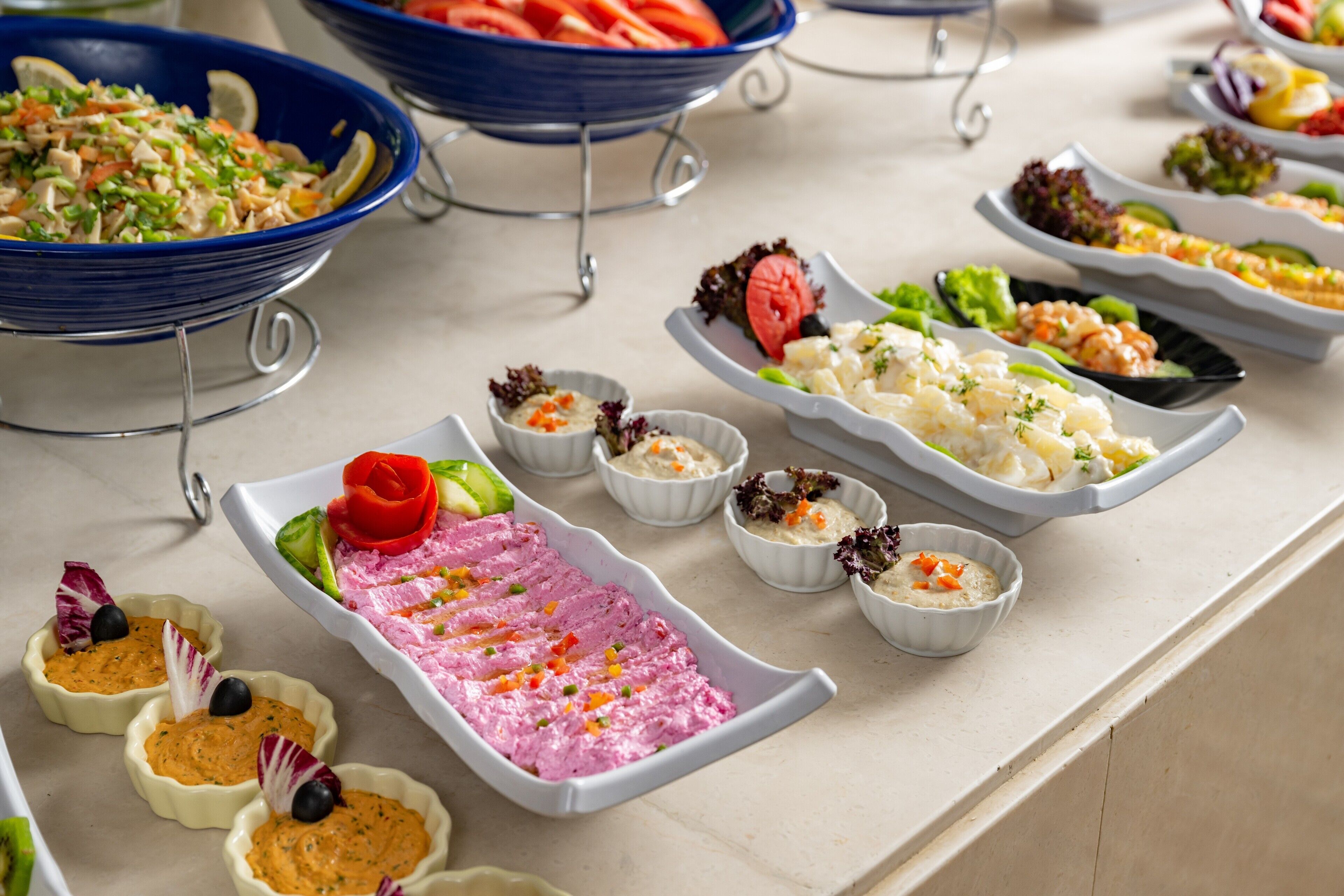 Una mesa de buffet con diversos platos, incluyendo una crema rosa, ensaladas y mariscos.