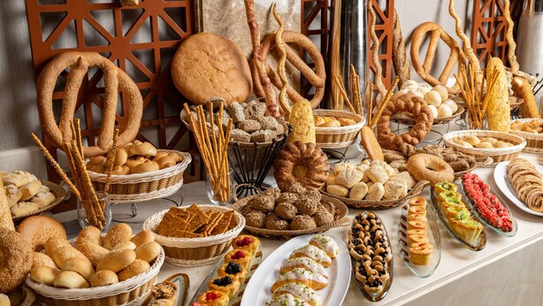 Diverse gebakken producten op een tafel, zoals pretzels, brood en gebak.
