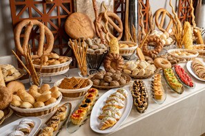Un'ampia varietà di prodotti da forno esposti su un tavolo, tra cui bretzel, pane e dolci.