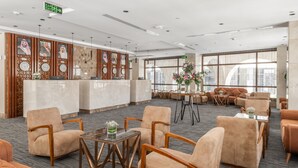 Een ruime lobby met een receptiebalie, zithoek en grote ramen.