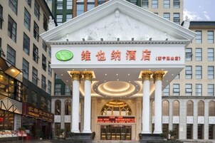 Entrada de hotel com fachada clássica, colunas e uma placa com caracteres chineses.