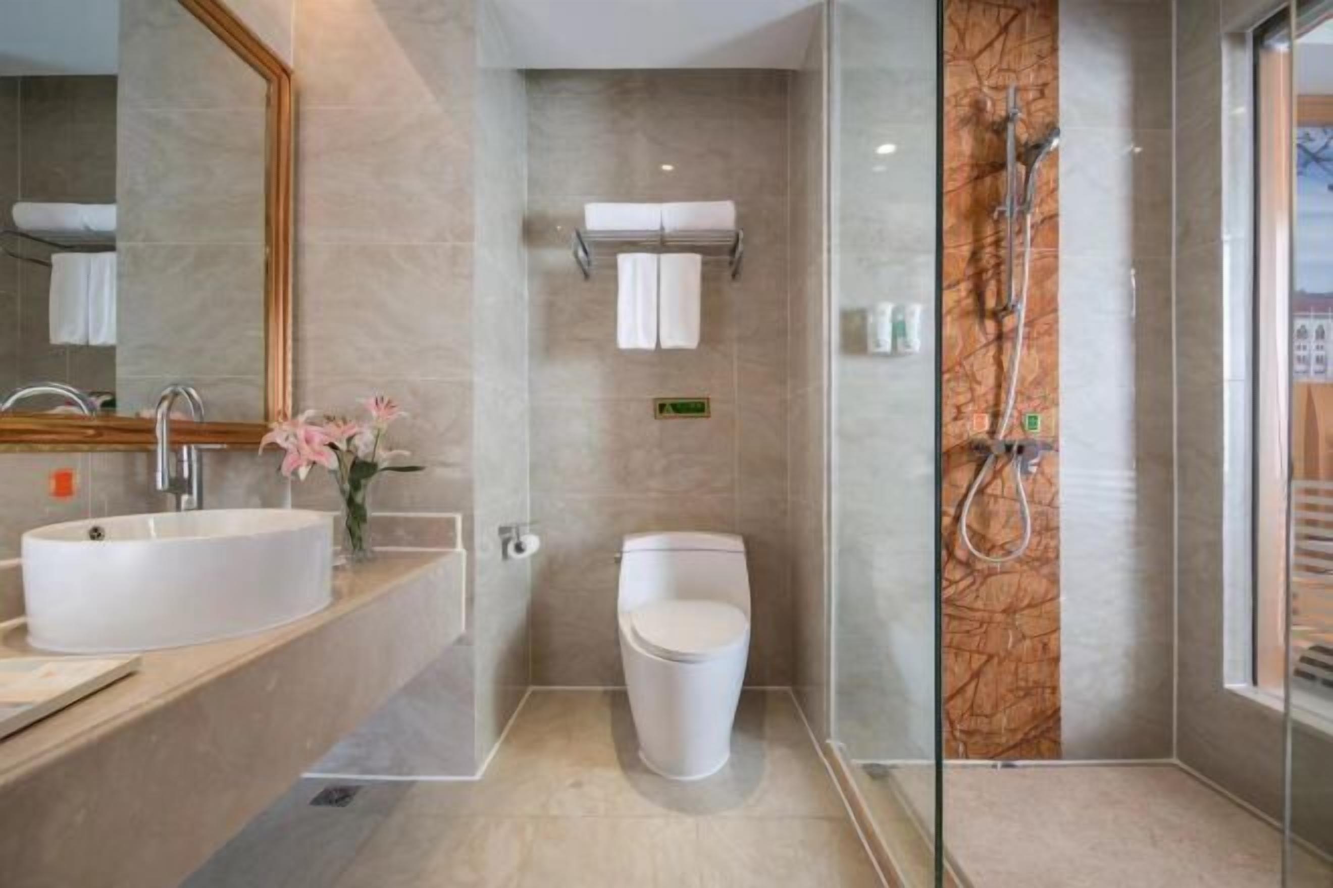 A modern bathroom with a large sink, toilet, and glass-enclosed shower.