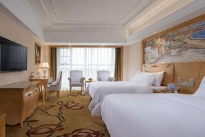 A hotel room with two beds, a desk, a TV, and a painting on the wall. - Vienna Hotel (Xinning Langshan) (Xinning)