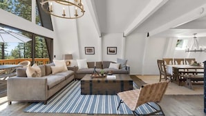 A spacious living room with a large sofa, a coffee table, and a dining area with a wooden table and chairs. - Incline Village Retreat: Hot Tub & Beach Access (Incline Village)