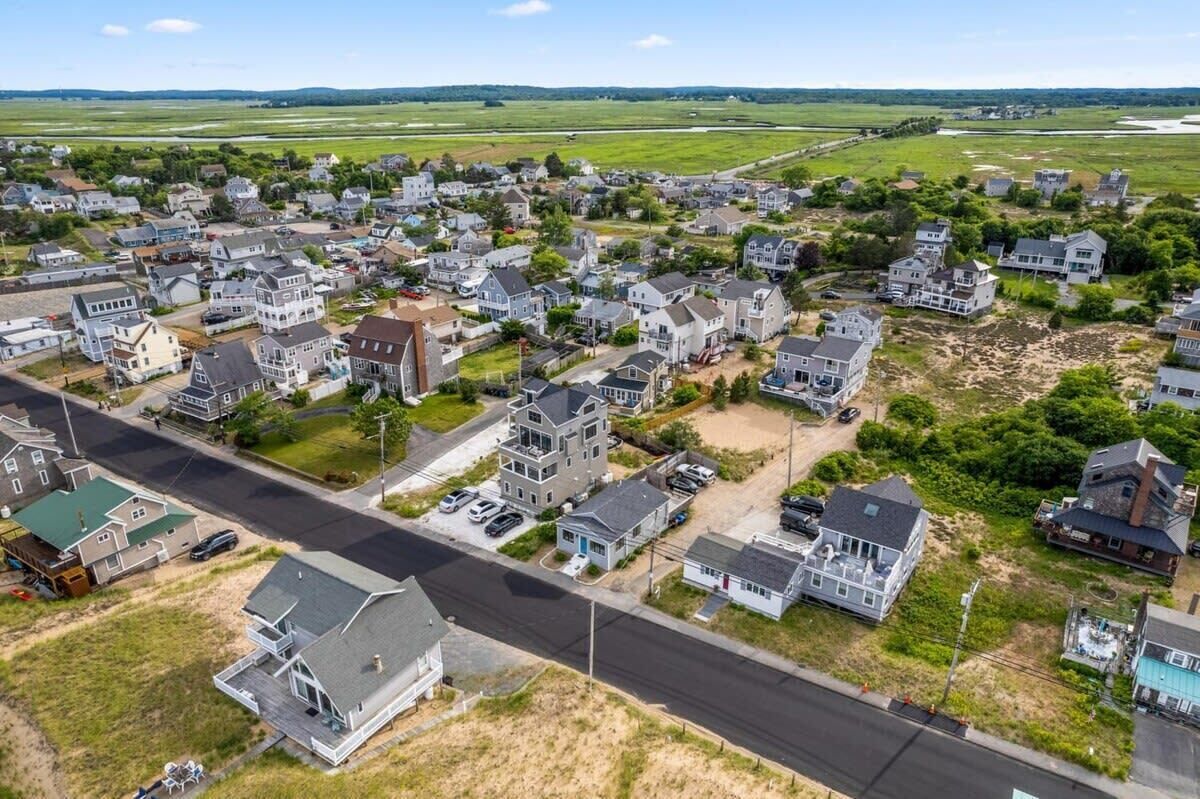 Vue aérienne d’un quartier résidentiel avec des maisons, des routes et des champs ouverts.