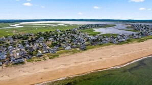 An aerial view of a coastal residential area with houses along the beach and a river running parallel to the shore. - The Nest | High-End Kitchen | Steps to Beach | A/C (Newbury)