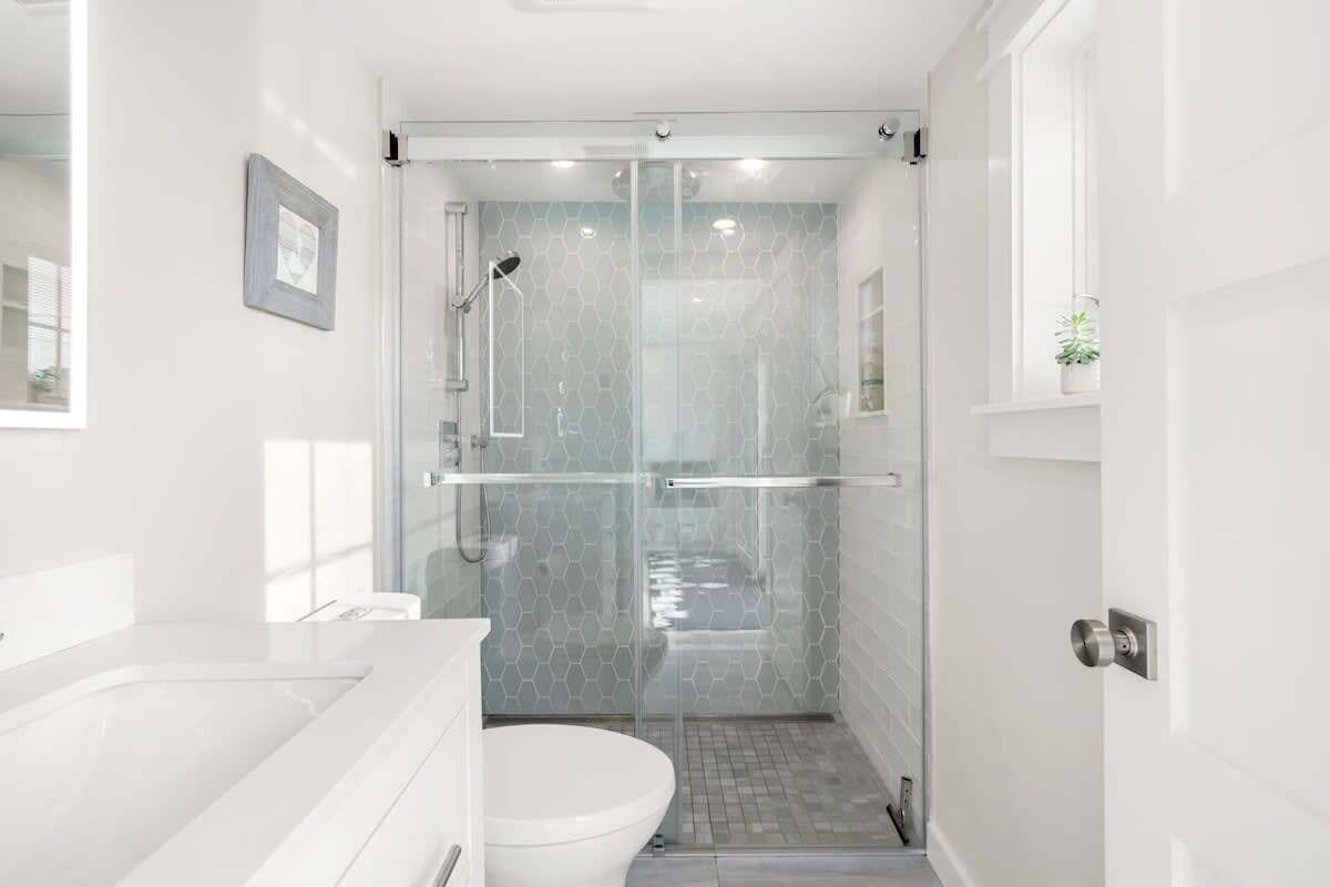 Une salle de bain moderne avec une douche à parois de verre, des toilettes blanches et un lavabo.