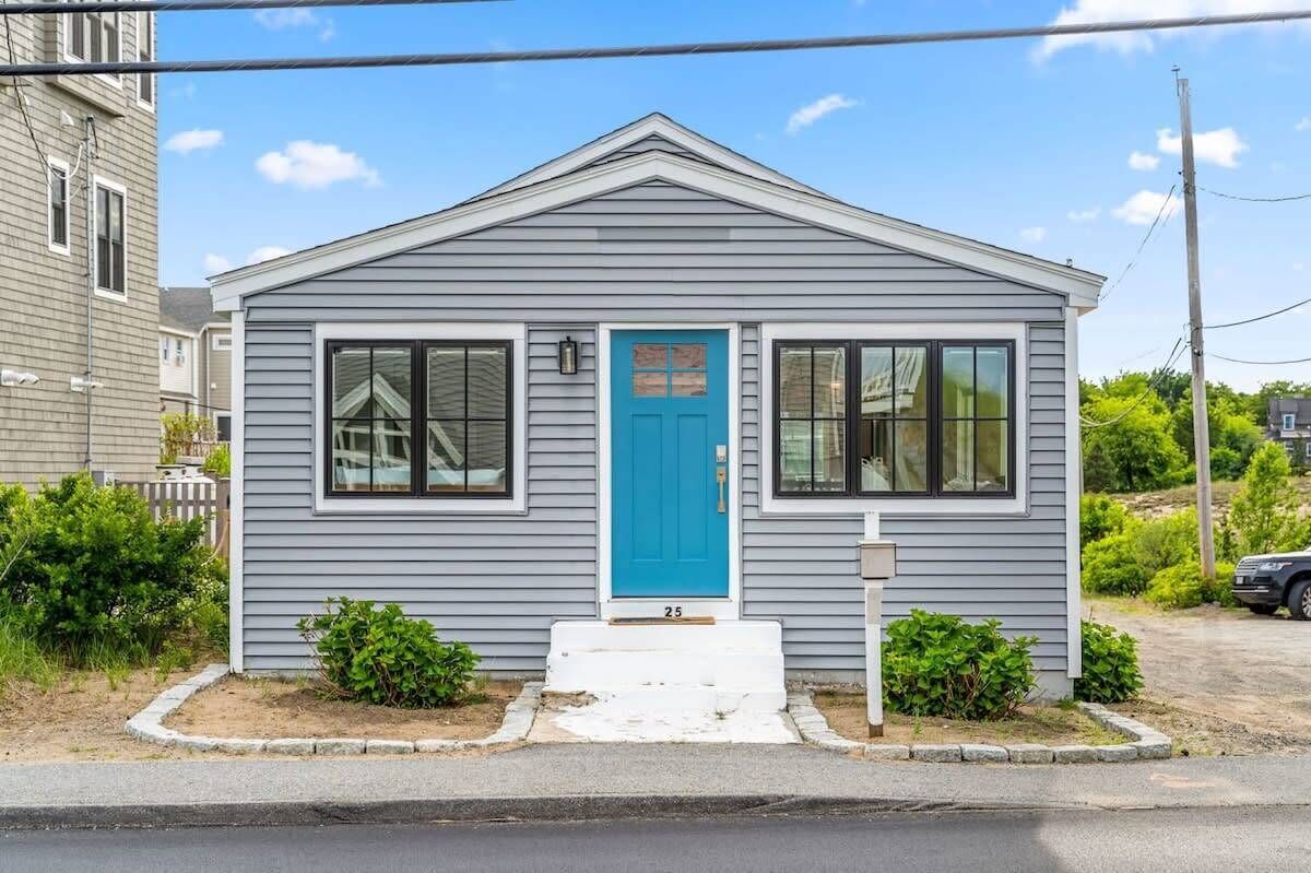 A small, single-story house with a blue front door, white trim, and a number '25' on the front steps.