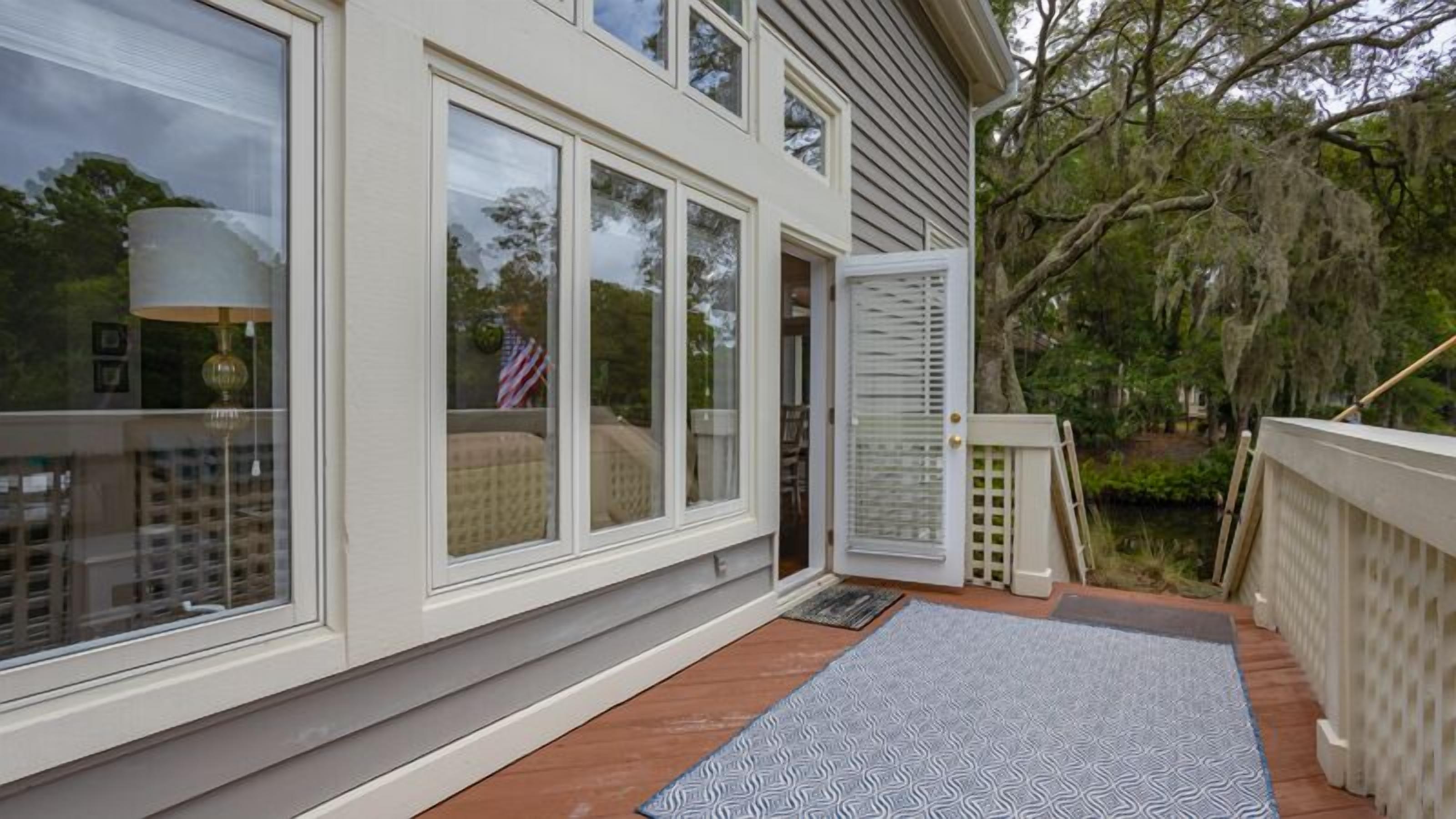 A house with large windows, a wooden deck, and a white exterior.