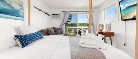 A bedroom with a large bed, a balcony, and a view of the outdoors.