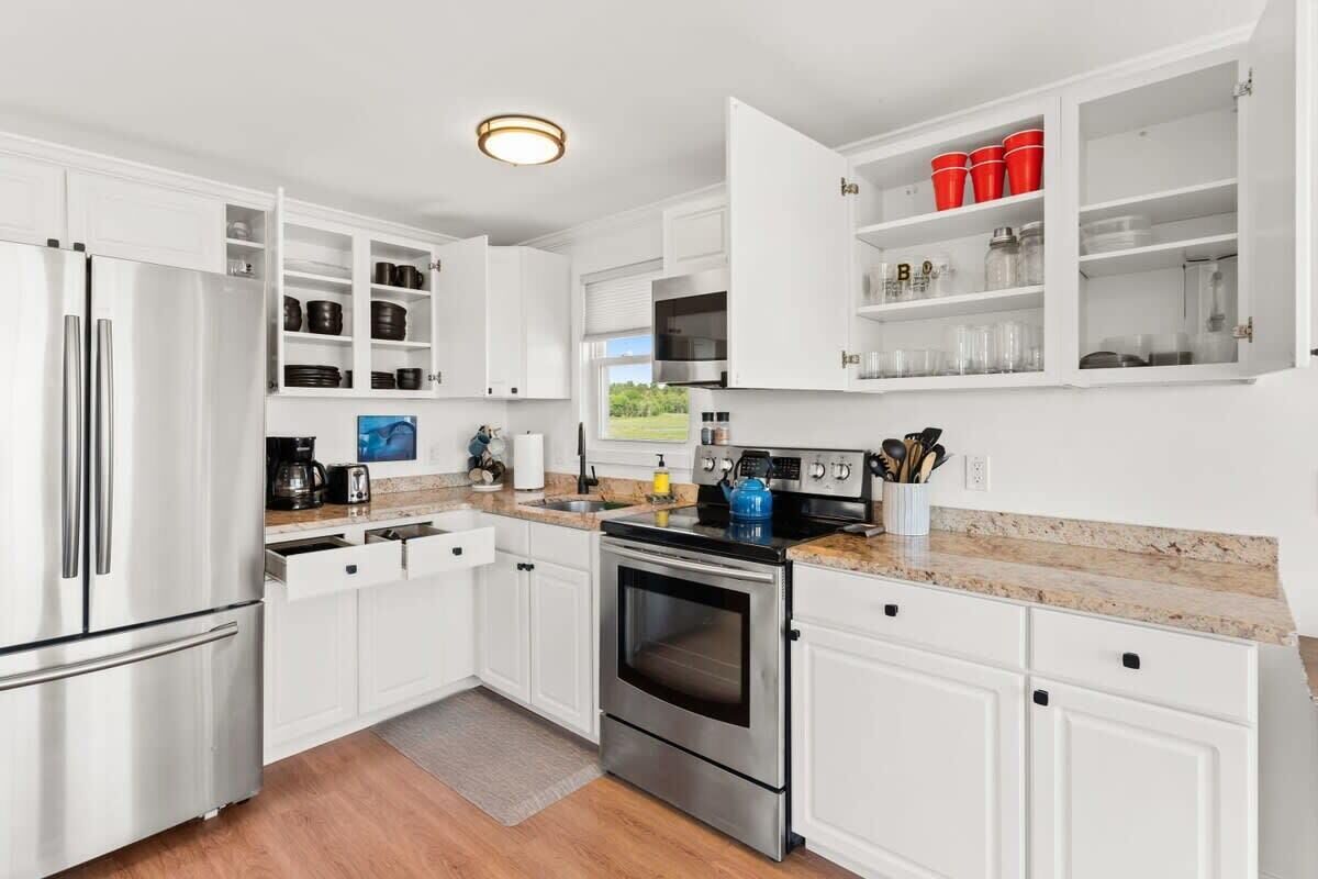 A modern kitchen with white cabinetry, stainless steel appliances, and a granite countertop.