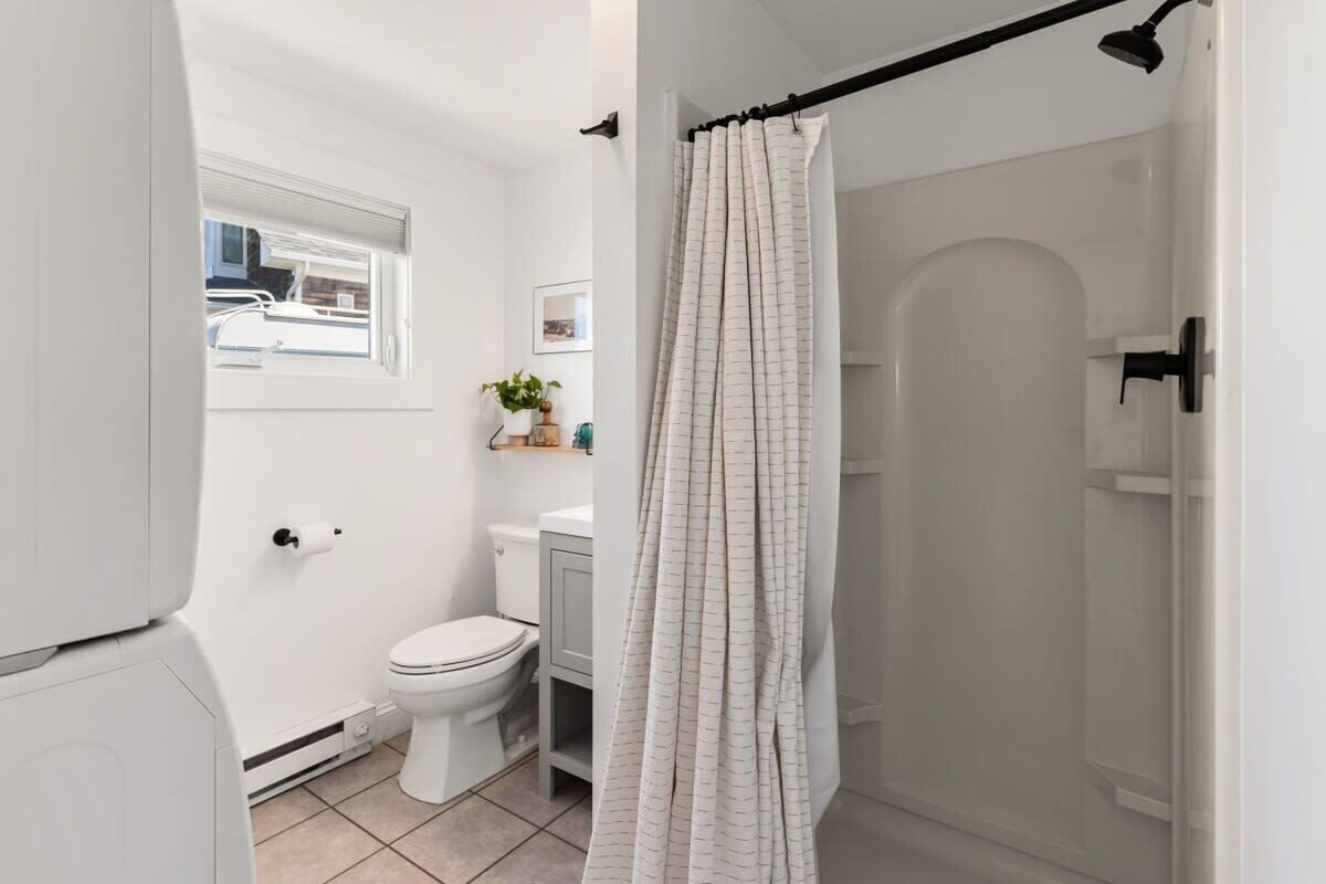 Une salle de bain comprenant des toilettes, un lavabo, une douche et une fenêtre.