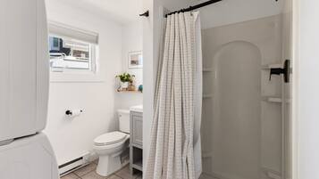 Une salle de bain comprenant des toilettes, un lavabo, une douche et une fenêtre.