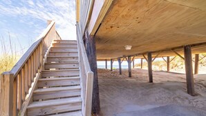 A wooden staircase leading to a covered area with a sandy floor. - Sweeping Ocean Views, Spectacular Sunrises, One-level living, KD3311 (Kill Devil Hills)