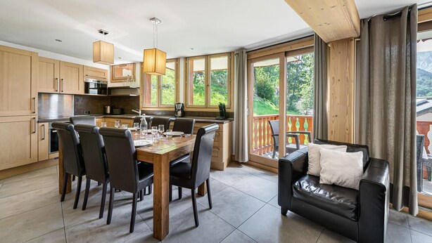A modern kitchen with wooden cabinets, a dining table with chairs, and a black leather sofa. - Wifi, ski-in/ski-out & foot of the slopes, Ground floor, balcony, parking, tv, 100m² (Saint-Martin-de-Belleville)