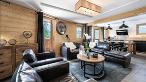 Un salon moderne avec des canapés en cuir, une table à manger en bois et un coin cuisine doté d’une grande fenêtre.