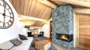 Un salón acogedor con chimenea de piedra, techo de madera y un gran reloj en la pared.