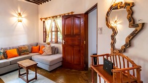 A cozy living room with a sofa, wooden side table, and a door with a mirror. - Luxury Holiday Villa - Private Chef - Pool - A/C (partly) (Ukunda)