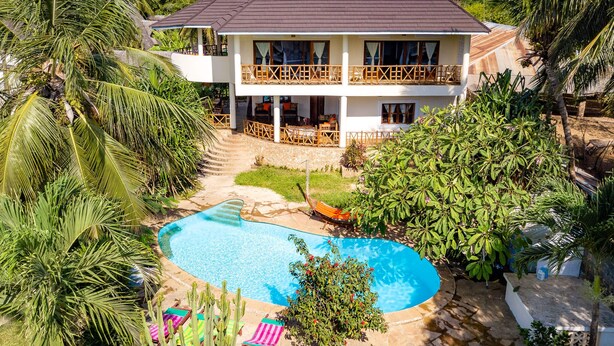 A two-story house with a swimming pool, surrounded by tropical vegetation. - Luxury Holiday Villa - Private Chef - Pool - A/C (partly) (Ukunda)