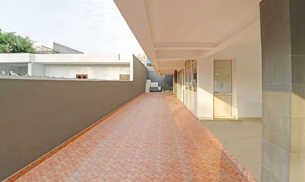 A corridor with tiled flooring, white walls, and a grey wall on one side.
