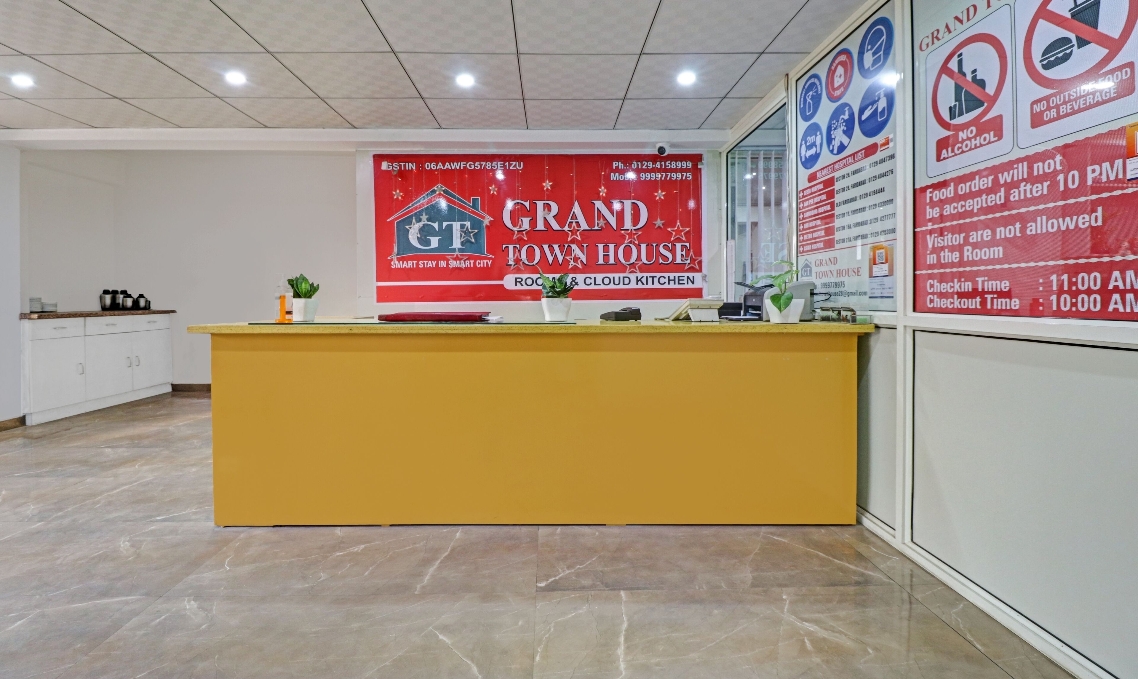 Un comptoir d’accueil d’hôtel avec une enseigne rouge indiquant qu’il s’agit du Grand Town House.