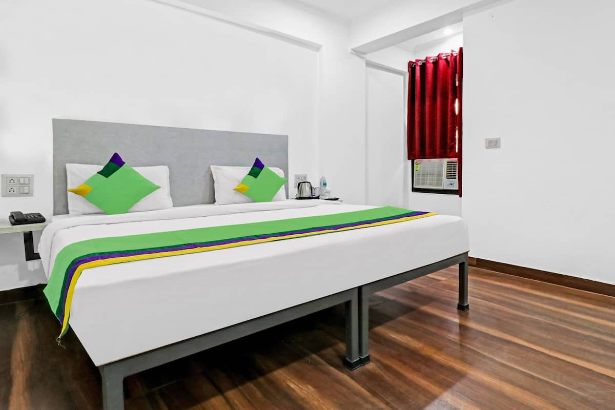 Quarto de hotel com uma cama, mesa de cabeceira, telefone e ar condicionado.