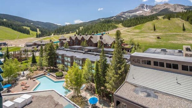 Un resort con piscina, varias edificaciones y un telón de fondo montañoso.