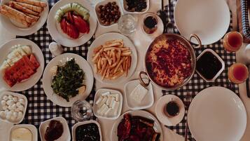 Uma mesa com diversos pratos, incluindo frituras, saladas e uma grande panela de comida, sugerindo um ambiente de refeição.