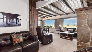 A spacious living area with a leather sofa, a stone fireplace, and a view of the beach. - West Newport Oceanfront Home & Patio on 65th St. (Newport Beach)