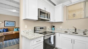 Una cocina moderna con armarios blancos, una estufa de acero inoxidable y un lavamanos doble.