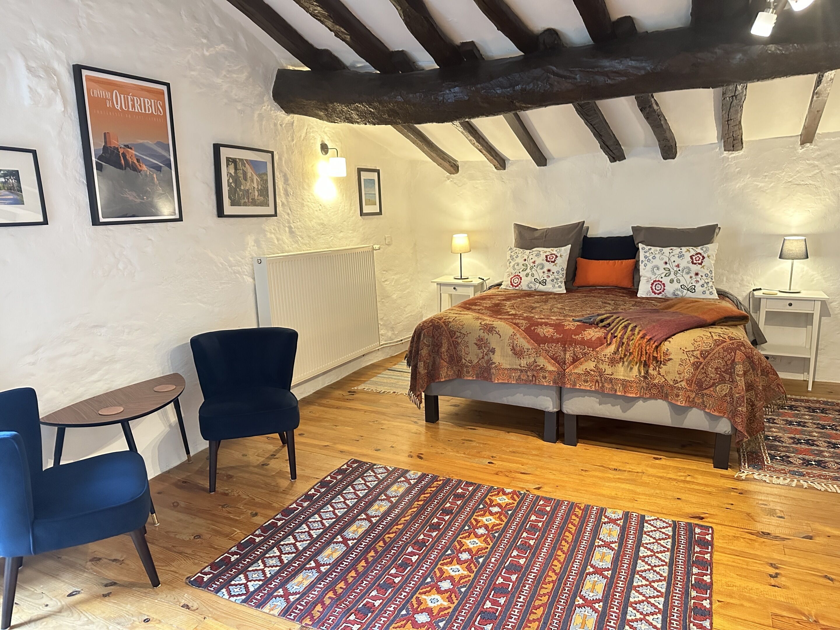 Ein gemütliches Schlafzimmer mit einem Bett, einem Sessel, einem kleinen Tisch und einem Teppich.
