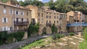 Un estrecho canal con edificios a ambos lados, un puente peatonal y un muro de piedra.