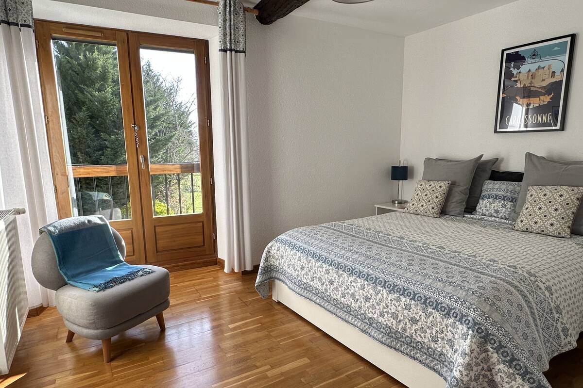 Un dormitorio con una cama grande, una silla, una ventana con cortinas y un cartel en la pared.