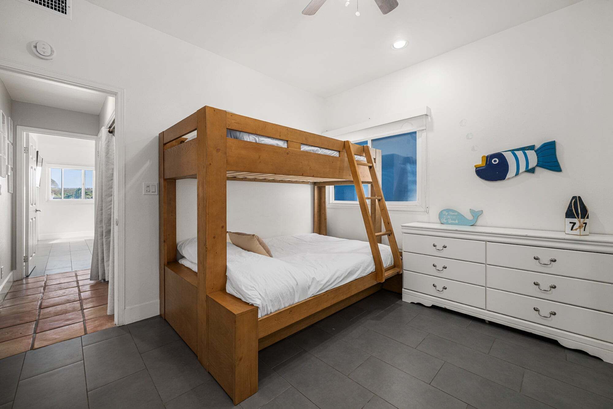 A bunk bed room with a window, a dresser, and a fish decoration on the wall.