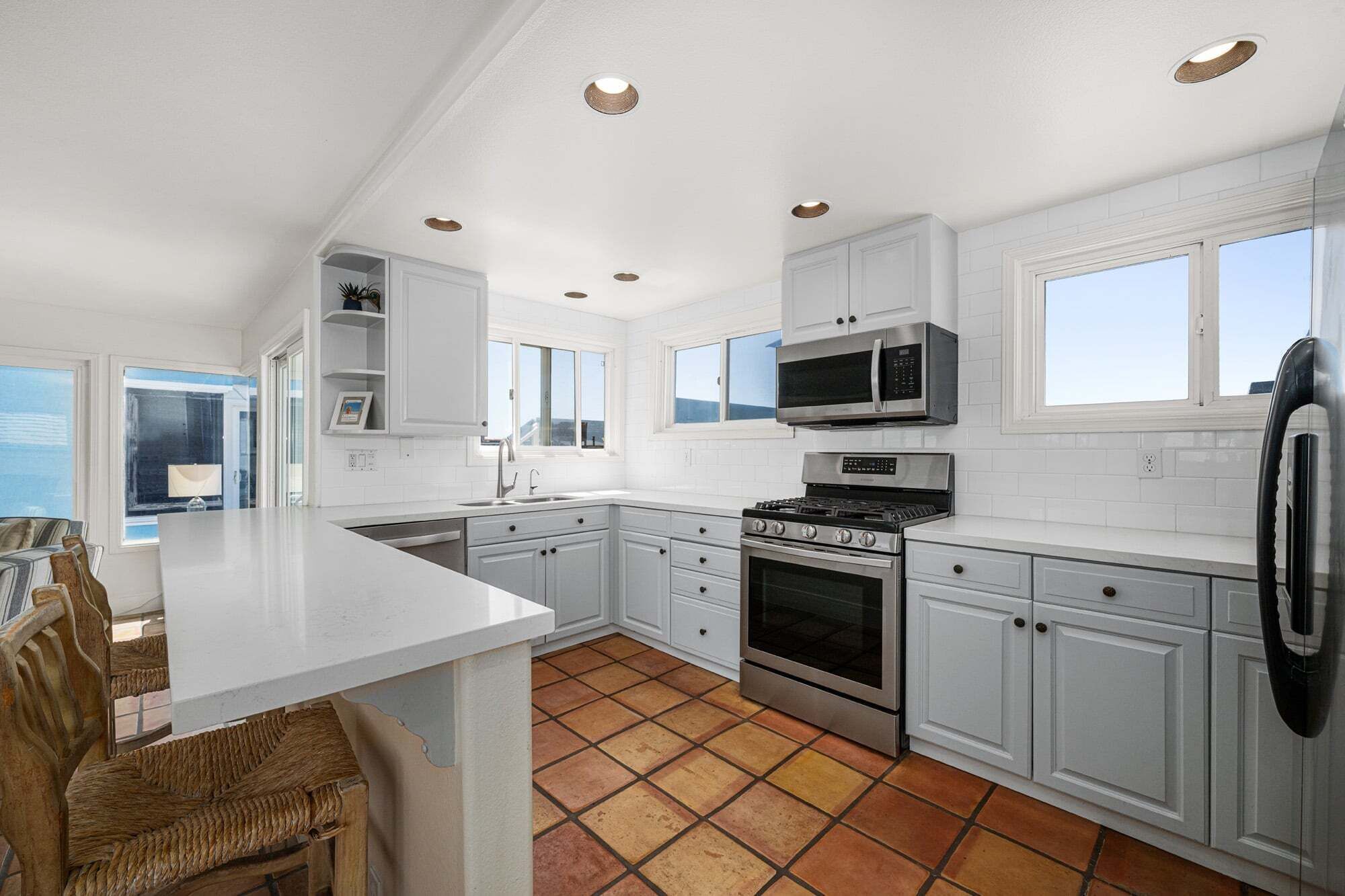 A modern kitchen with white cabinetry, a central island, a stove, microwave, and a refrigerator.