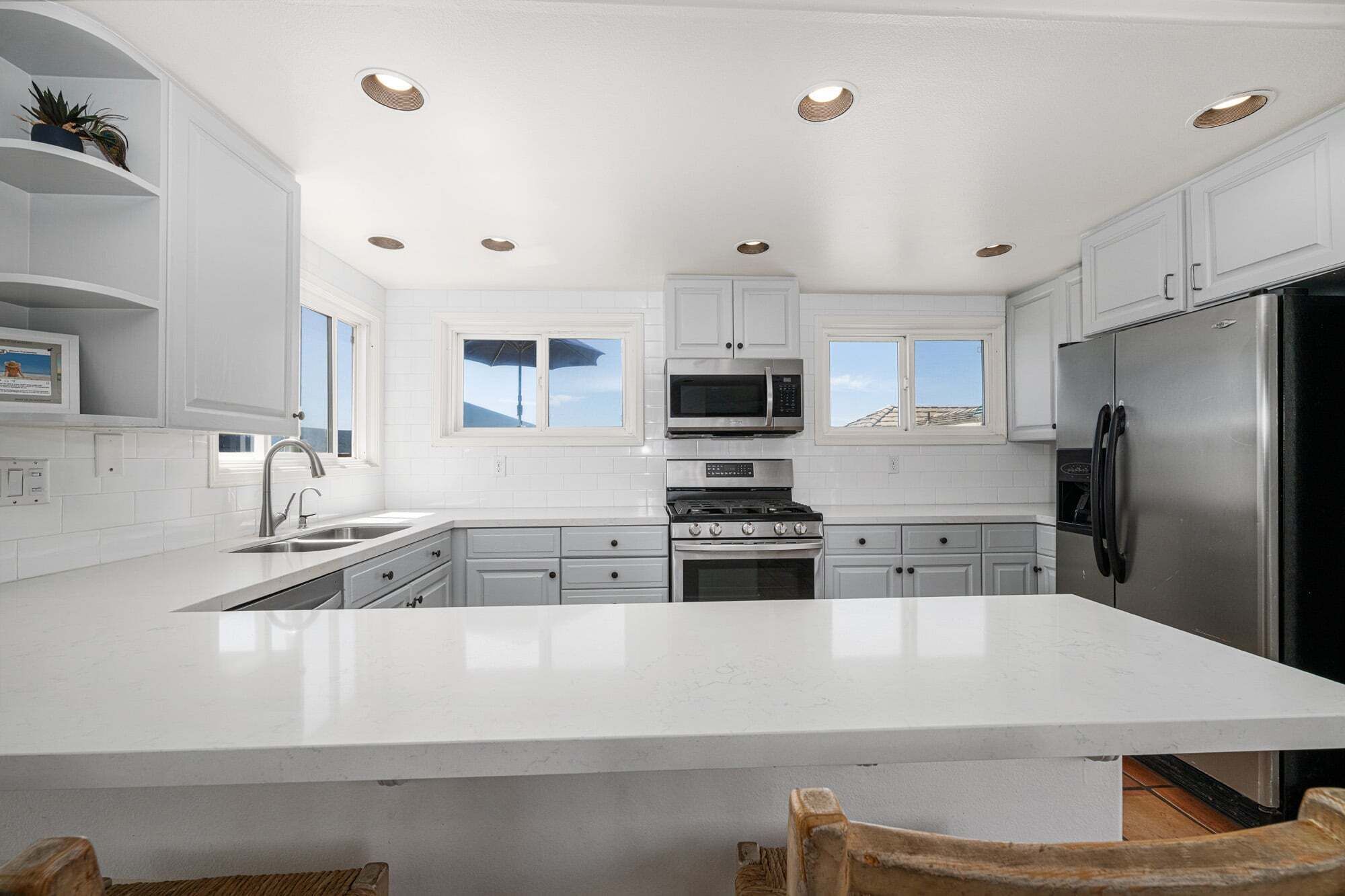 A modern kitchen with white cabinetry, a stainless steel refrigerator, a microwave, and an oven.