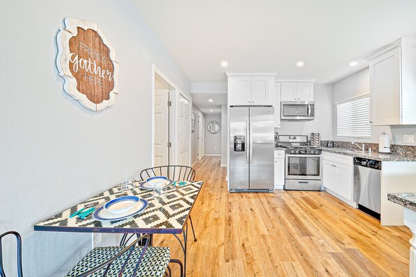 A modern kitchen with white cabinets, stainless steel appliances, and a wooden floor.