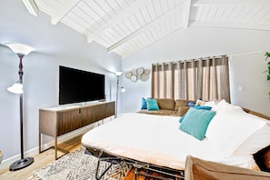 Un dormitorio con cama, televisión, mesita de noche y lámpara.