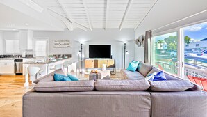 Ein modernes Wohnzimmer mit einer großen Couch, einer Küchenzeile und einem Balkon mit Blick auf die Stadt.