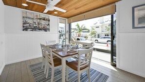 Un espace repas doté d’un plafond en bois, de murs blancs et offrant une vue sur la rue.