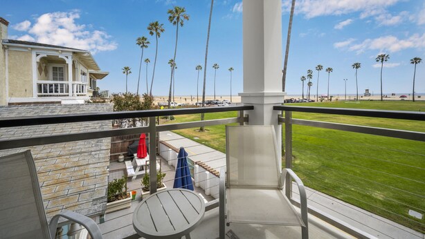 Een balkon met uitzicht op een strand, palmbomen en een gebouw met een veranda.
