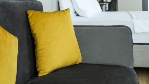 A modern hotel room with a grey sofa, a bed with white linens, and wall-mounted lamps. - Fontana Verde (Istanbul)
