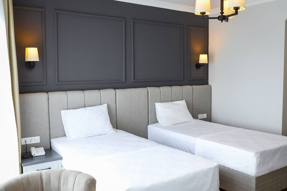Une chambre d’hôtel avec deux lits simples, une table de chevet avec un téléphone et une chaise.