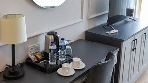 A hotel room with a desk, a flat-screen TV, a mirror, a lamp, a coffee maker, and a chair. - Fontana Verde (Istanbul)