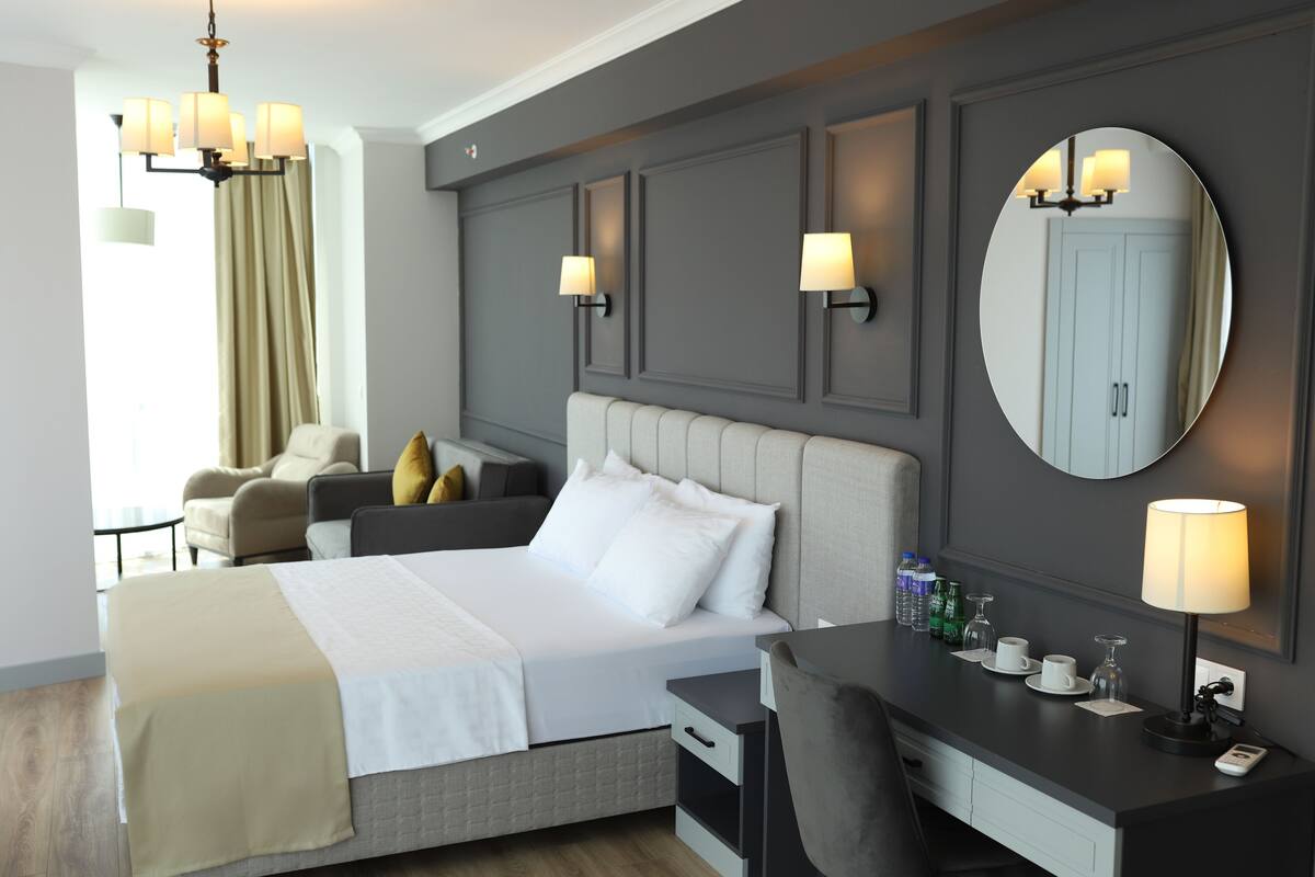 Une chambre d’hôtel comprenant un lit, une table de chevet, un bureau, une chaise et un grand miroir.