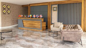 A lobby with a reception desk, a sofa, a chair, and a coffee table. Flags are displayed on the wall. - Fontana Verde (Istanbul)
