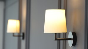 A modern hotel room with a grey wall, two wall-mounted lamps, and a white headboard. - Fontana Verde (Istanbul)