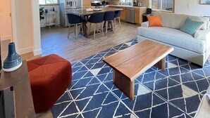 Ein moderner, offener Wohnbereich mit Küche, einem Esstisch mit Stühlen, einer Couch und einem Couchtisch.