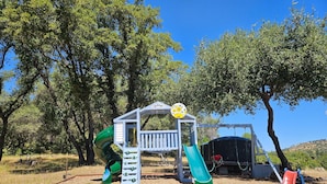 Ein Spielplatz mit Rutsche, Klettergerüst und überdachtem Bereich.